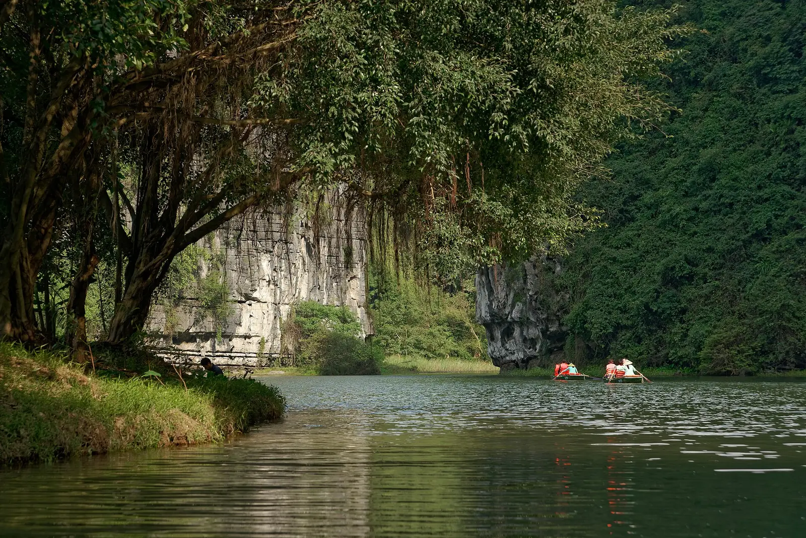 Kalksteenrotsen en een rivier met bootjes in het landschap van Trang An bij Ninh Binh