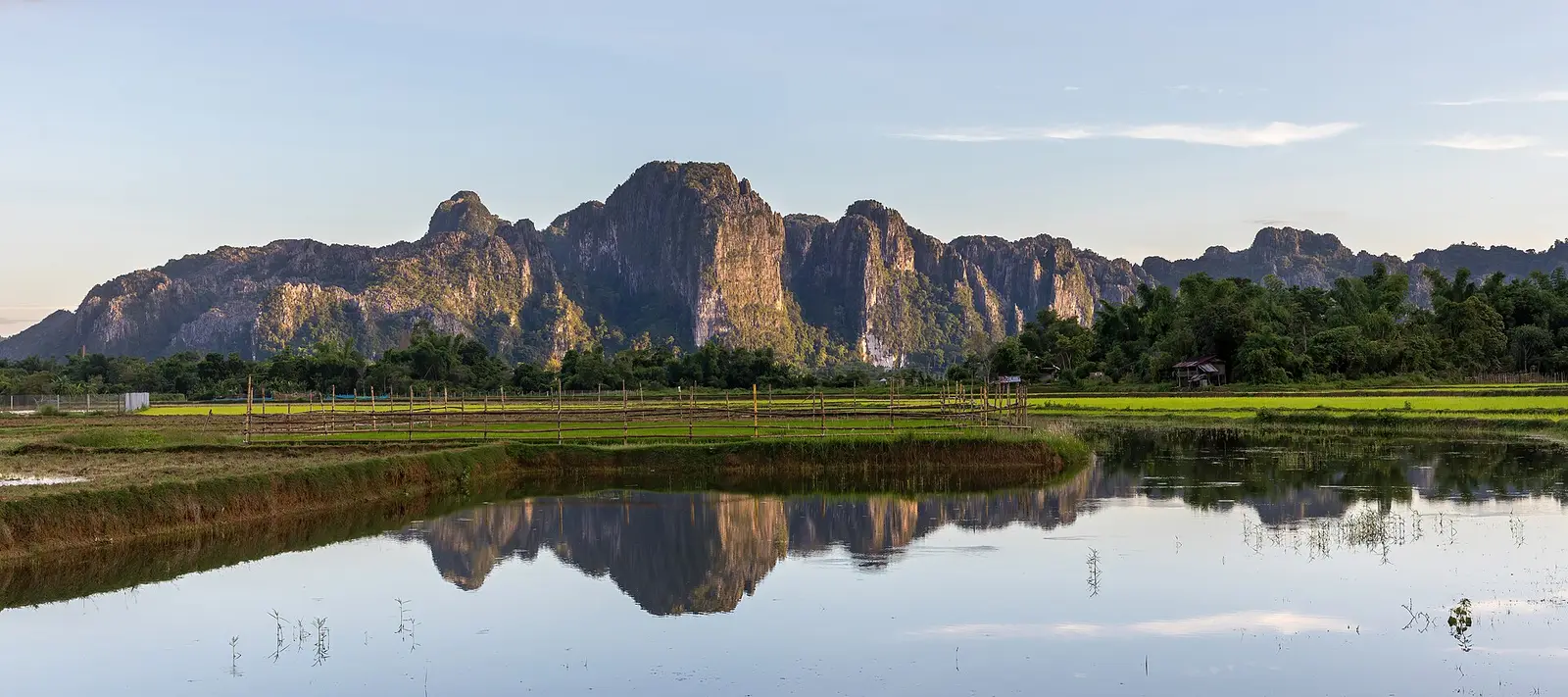 Karstbergen spiegelen in het water bij Vang Vieng bij zonsondergang