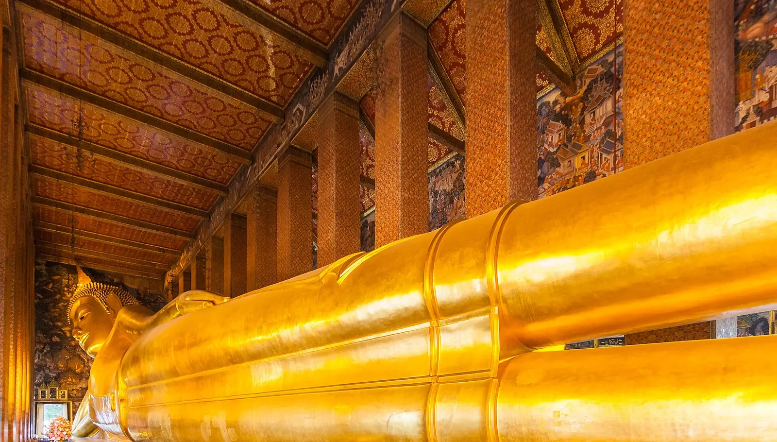 De gouden liggende Boeddha in Wat Pho, Bangkok, met beschilderde pilaren en wanden eromheen