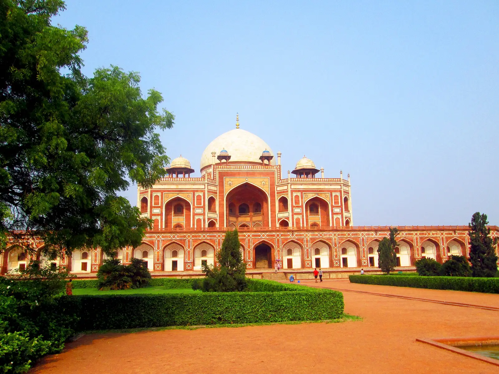 Het graf van Humayun in Delhi gezien over een zandpad en een tuin met lage heggen
