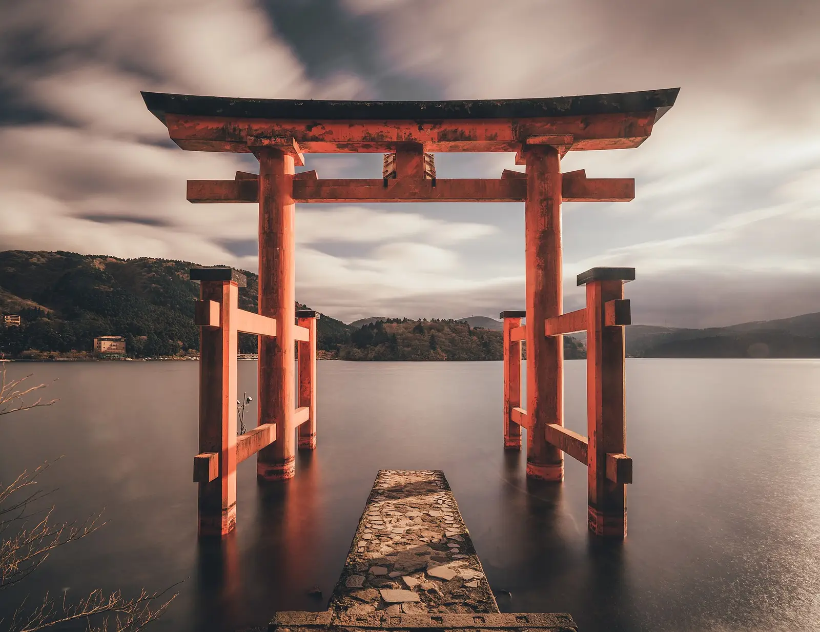 De rode torii van de Hakone-schrijn staat in het water van het Ashi-meer, met beboste bergen erachter