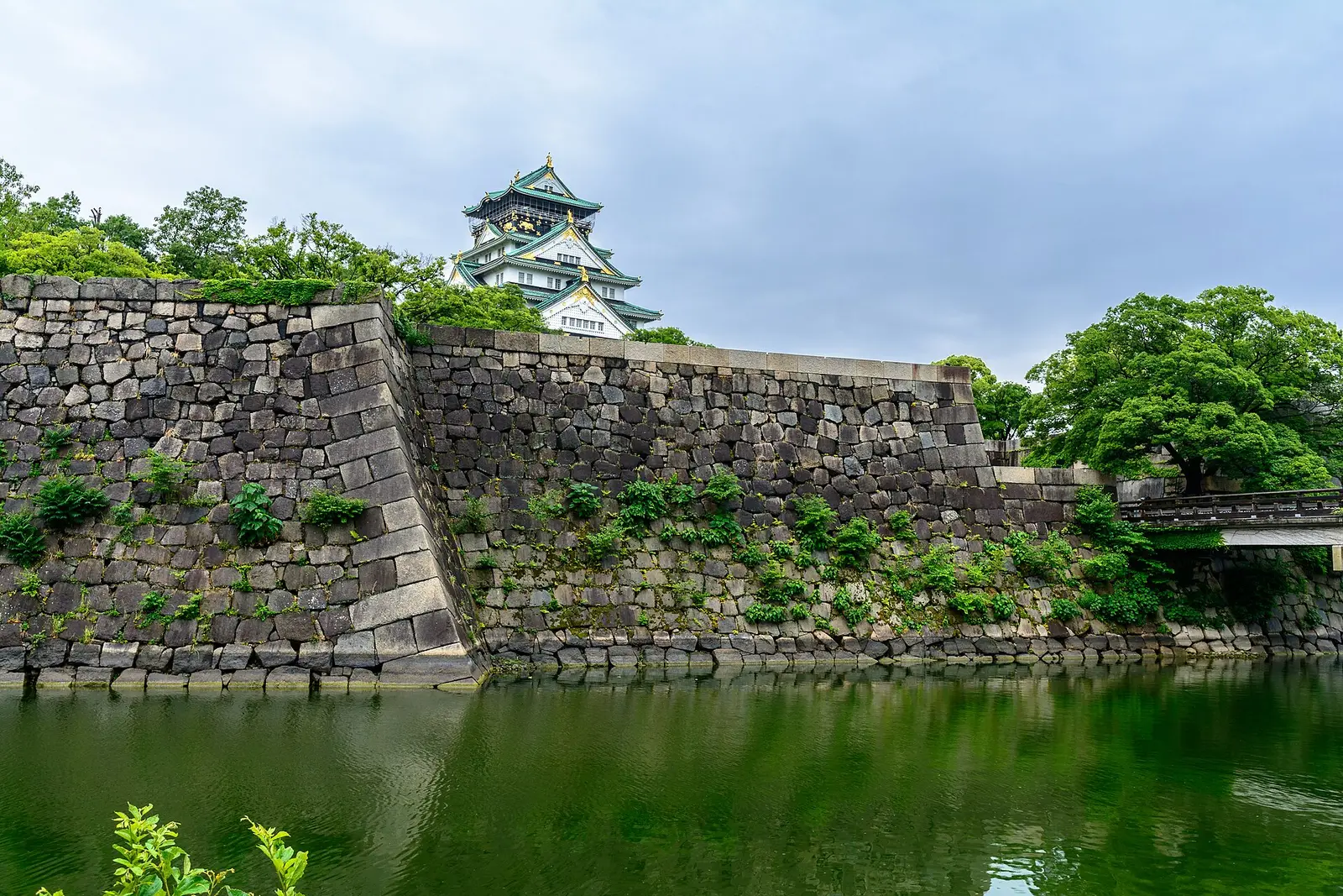 De toren van het kasteel van Osaka boven de oude stenen muren en de gracht