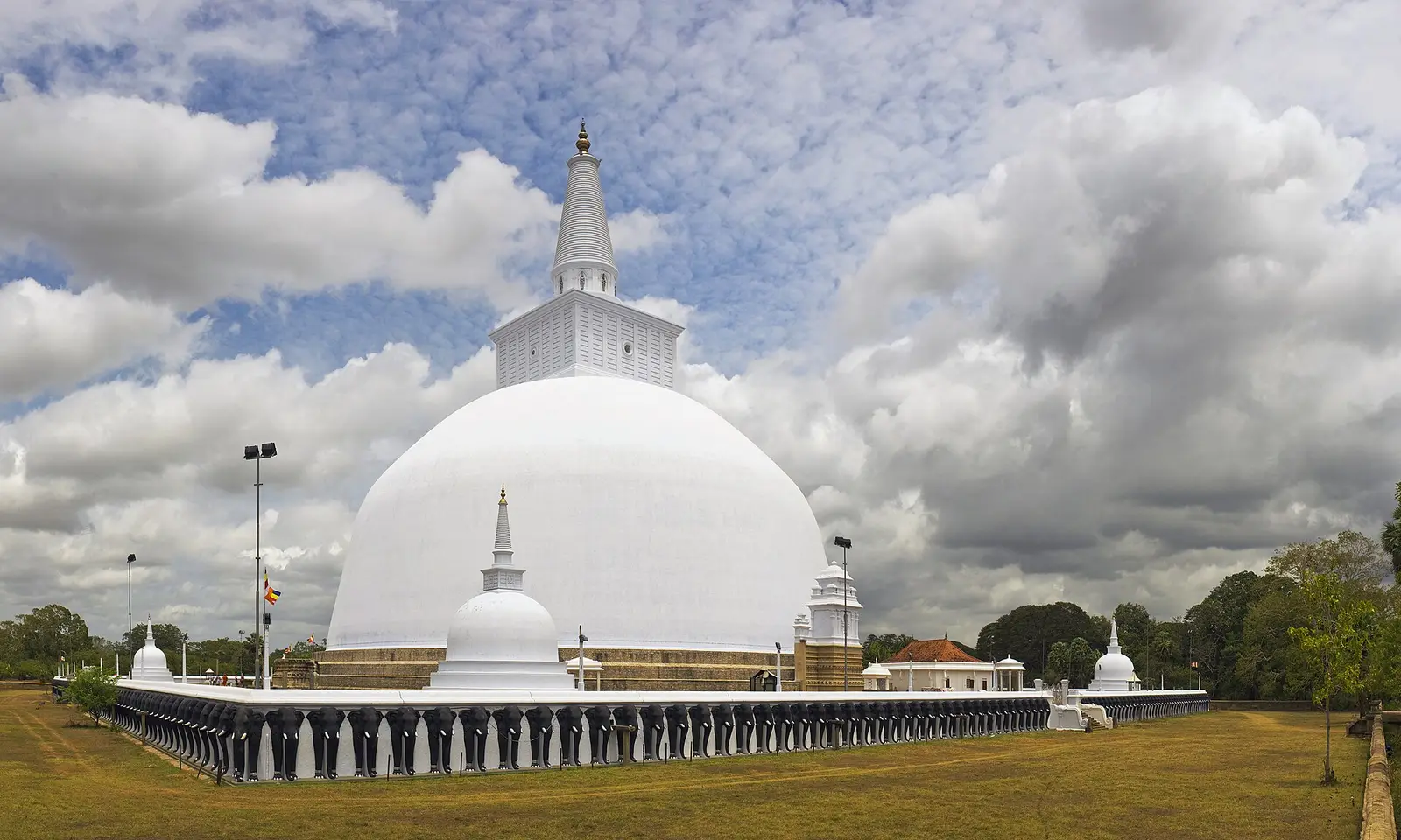 De witte koepel van de Ruwanwelisaya in Anuradhapura onder een bewolkte lucht, met een gazon eromheen