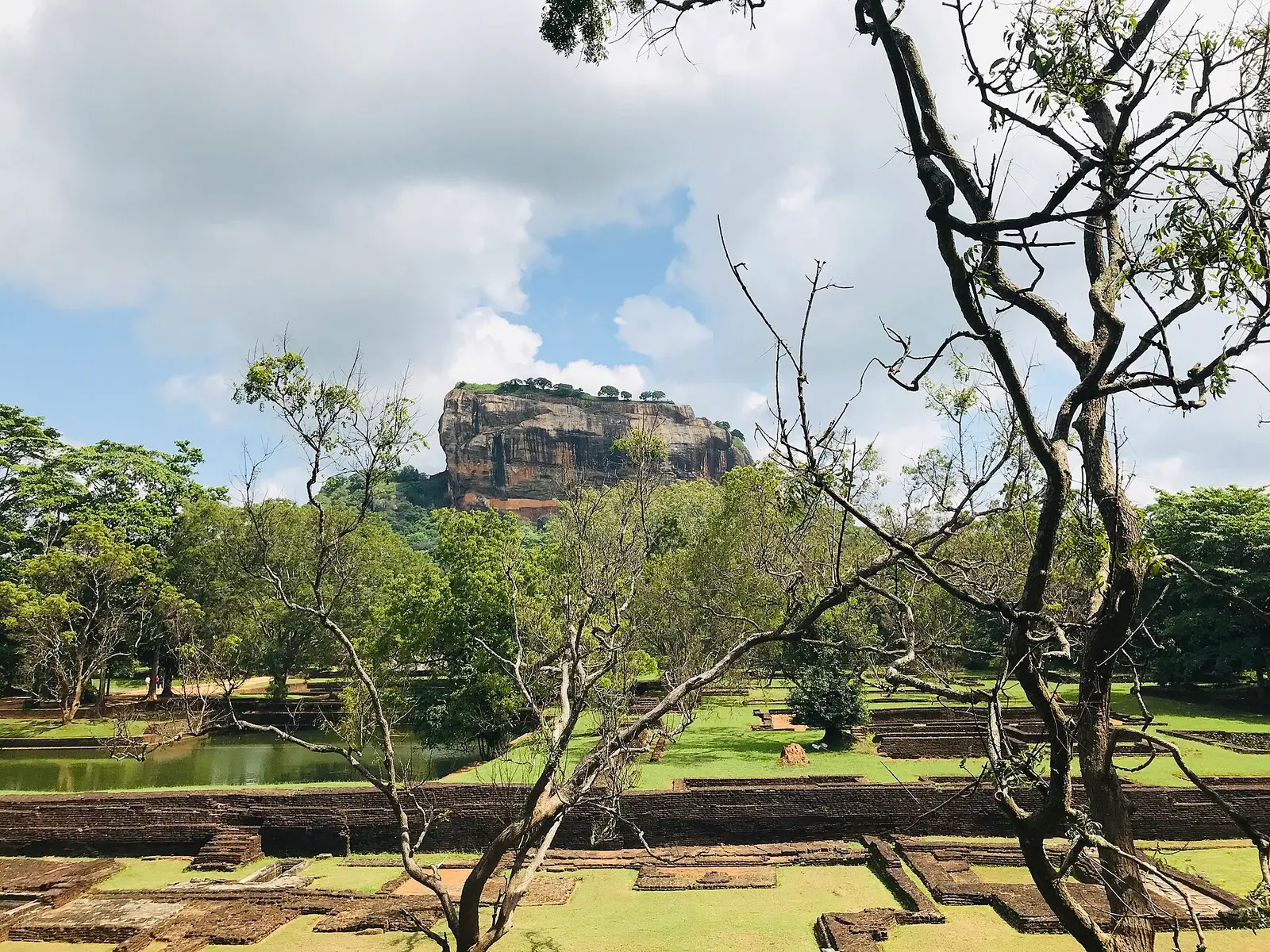 De Leeuwenrots van Sigiriya boven het groen, gezien over de waterpartijen van het onderste terrein