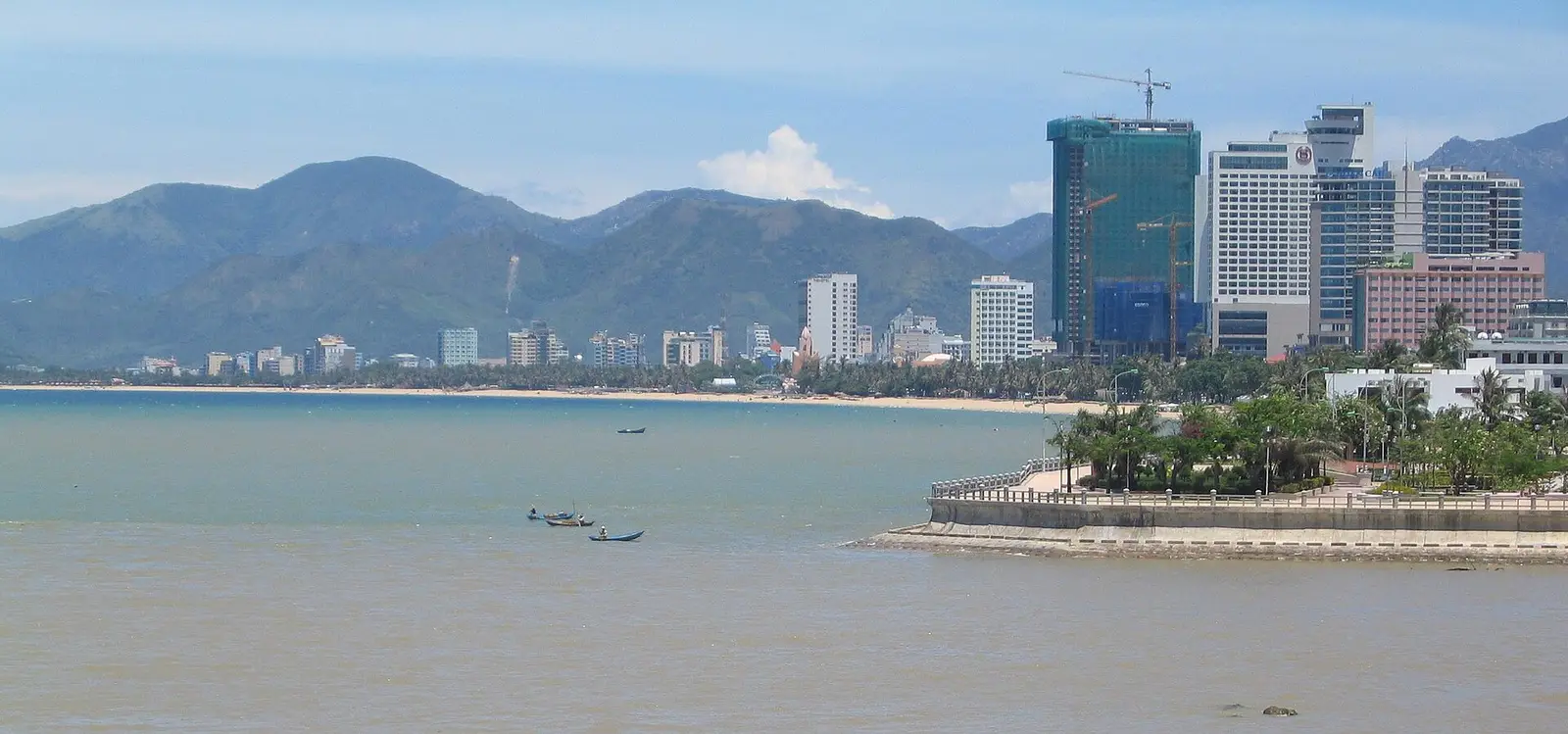 De baai van Nha Trang met de kustlijn, hoge gebouwen en groene bergen erachter