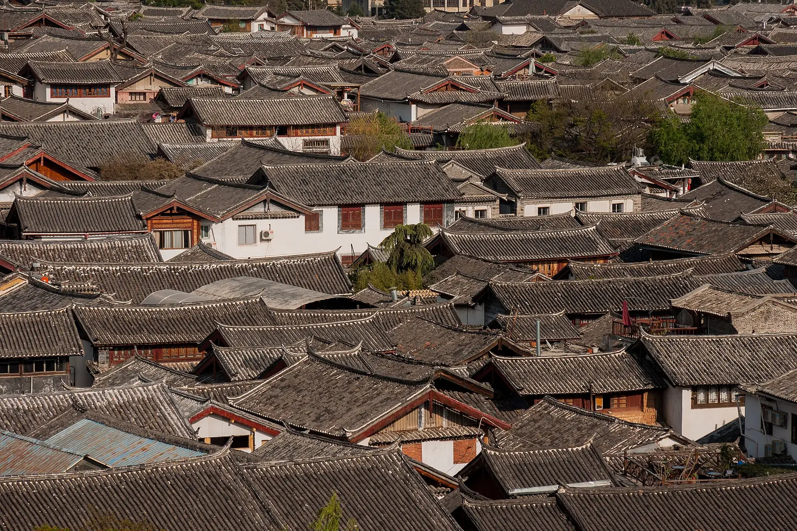 Dicht opeenstaande grijze daken van de oude stad van Lijiang, van bovenaf gezien